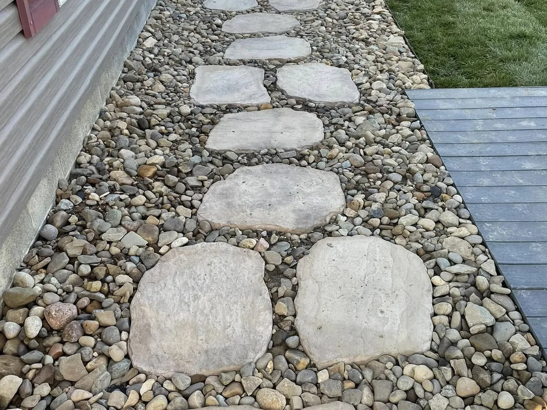 Concrete: cast stepping stones set in a river rock path beside a house