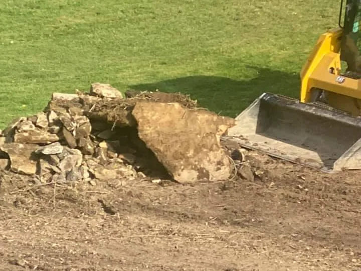 Excavation: a machine bucket pushing into a pile of dug out rock and soil