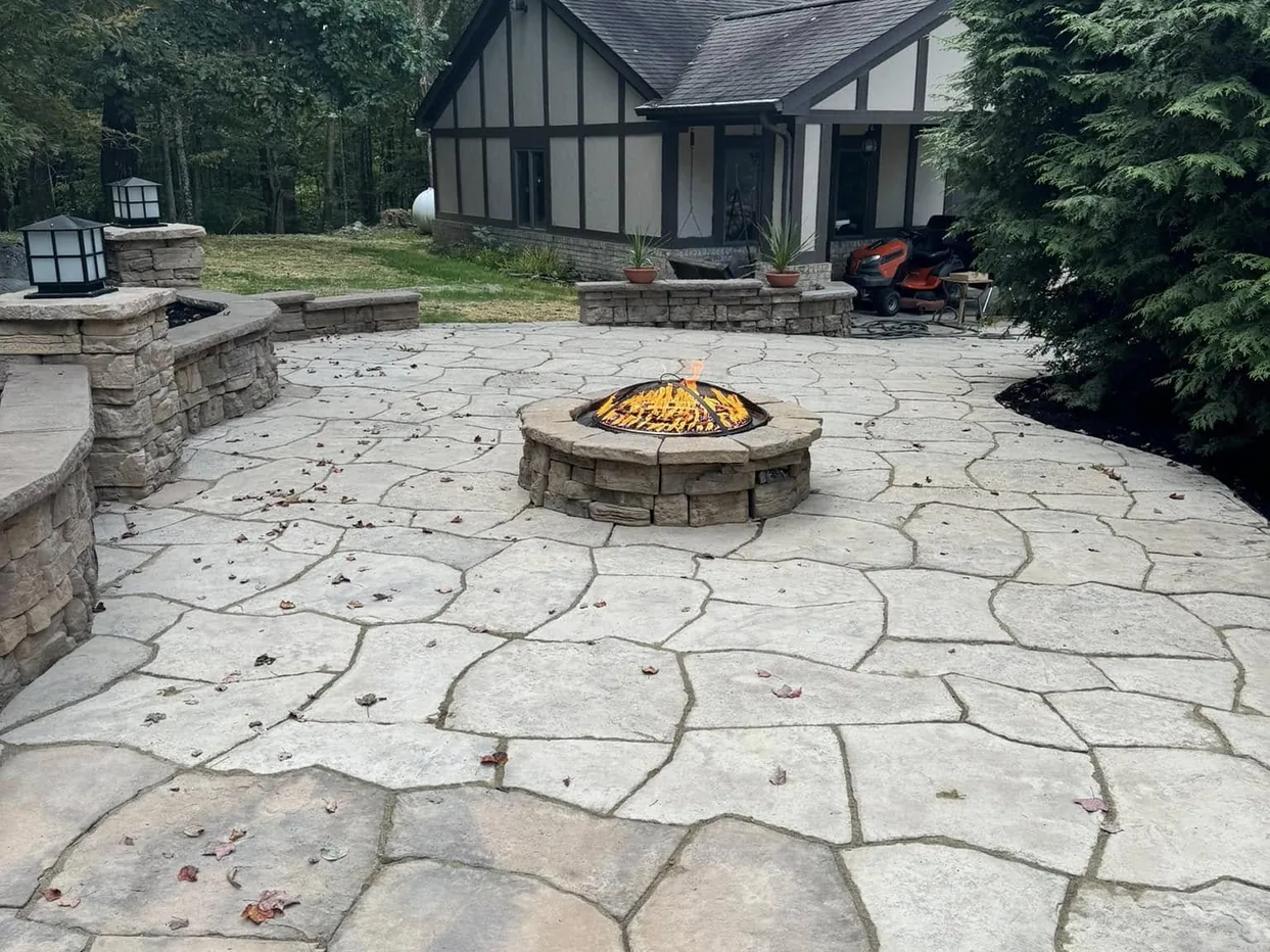 Fire pits: a stone fire pit centered in a flagstone pattern patio behind a home