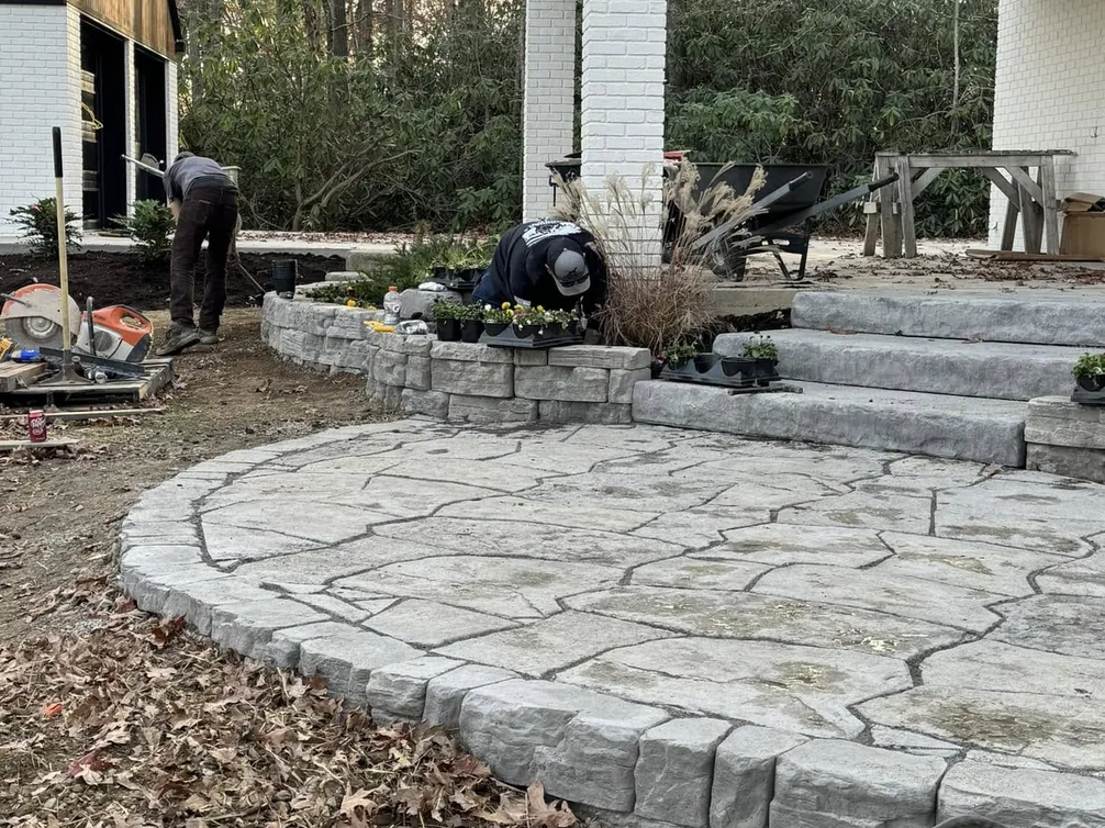 Hardscaping: a crew laying a curved flagstone paver patio and steps beside a covered porch