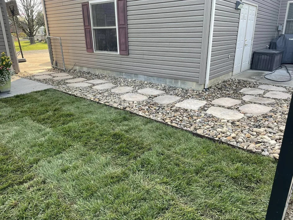 Land clearing: new sod and a stepping stone path set in river rock beside a house
