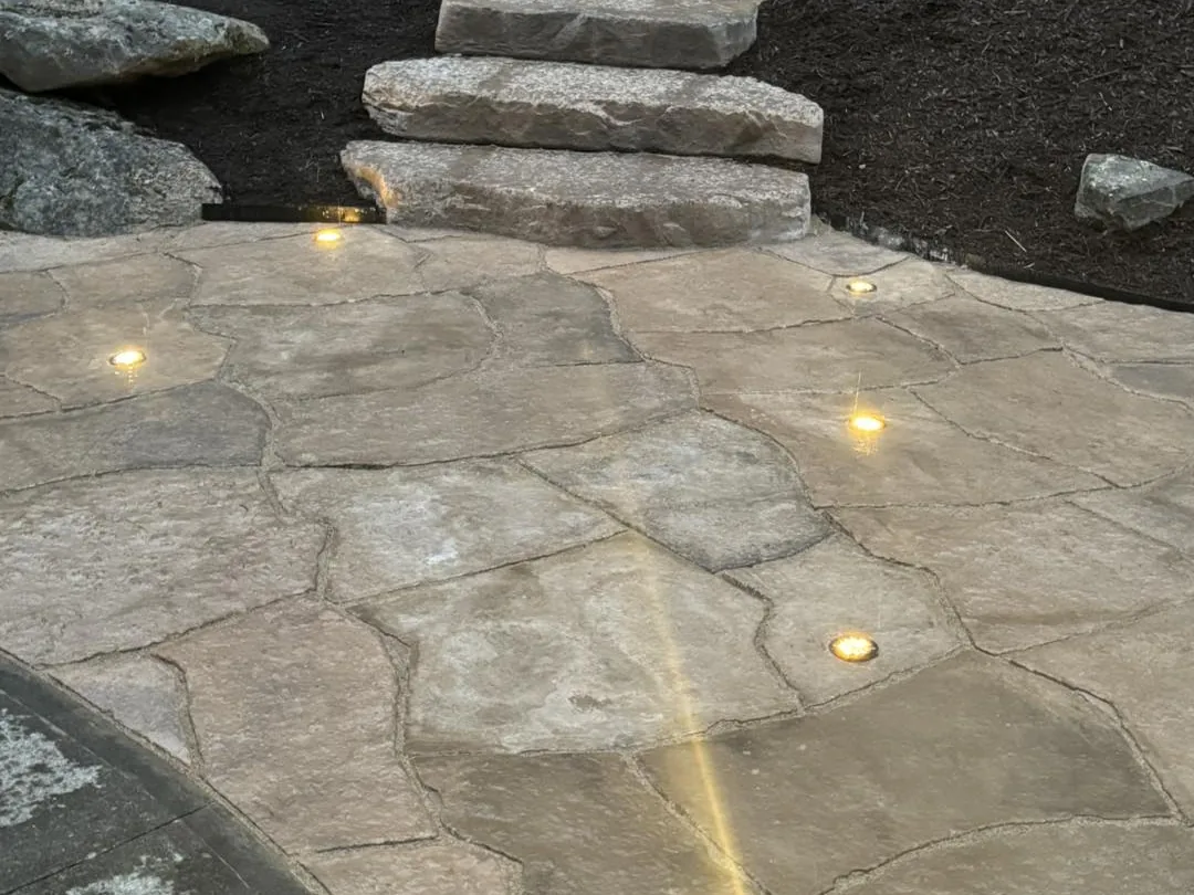Outdoor lighting: lights set in a flagstone patio below slab steps after dark