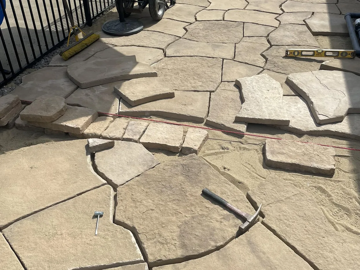 Paver patios: flagstone pattern pavers being laid on a compacted base