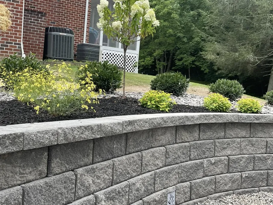 Retaining walls: a curved block retaining wall holding a mulched planting bed