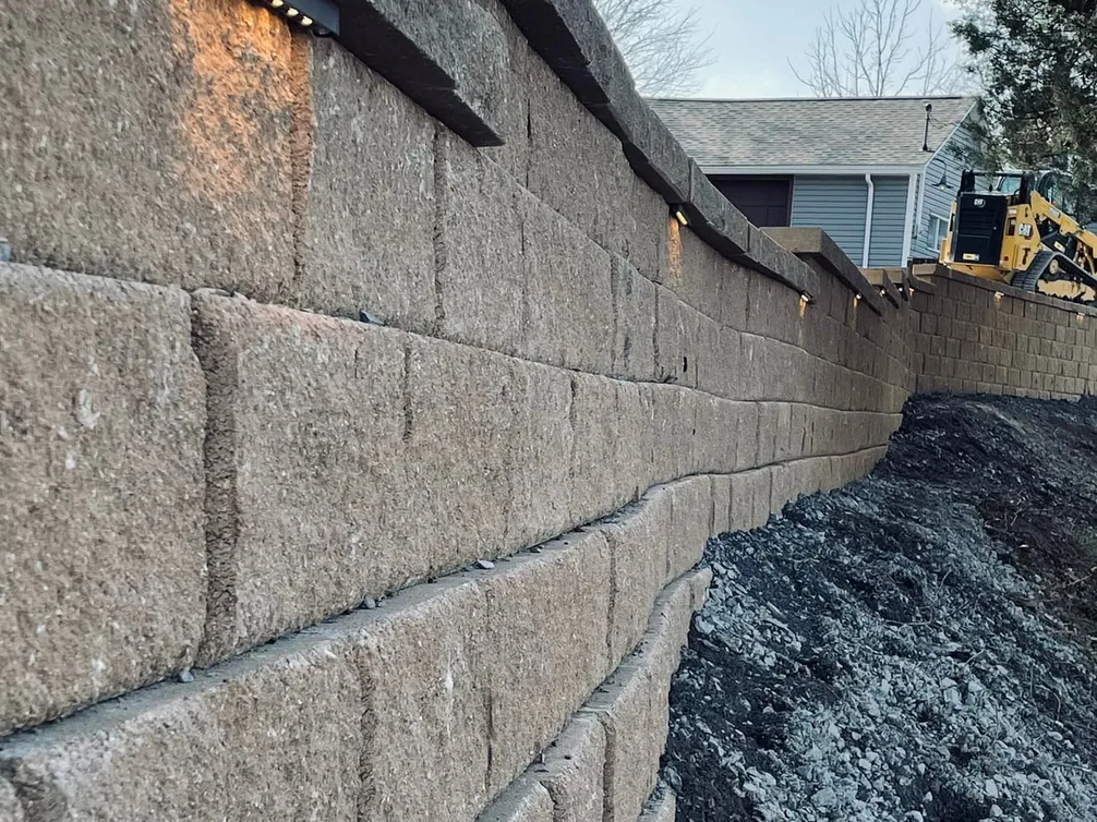 Retaining walls: a tall block retaining wall with cap lights and fresh backfill