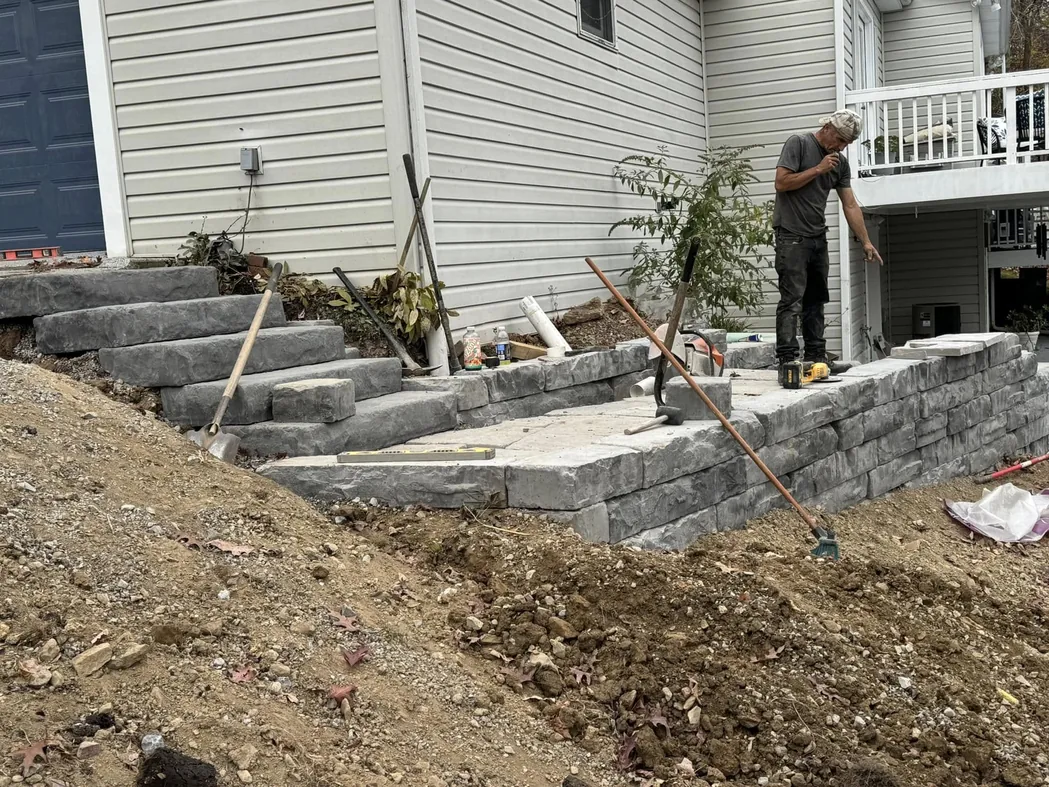 Retaining walls: a crew member building a block retaining wall and steps along a house