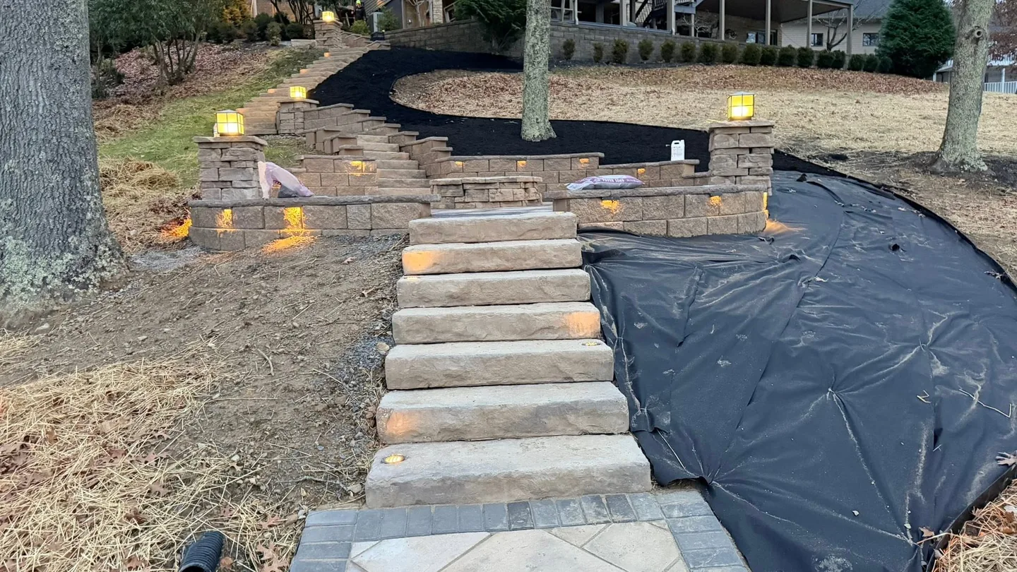 Hardscaping: lighted stone steps and block walls climbing a hillside yard