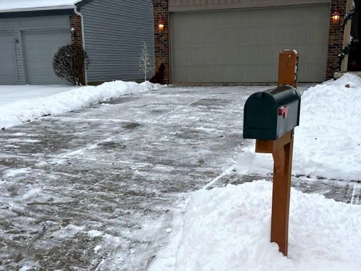 Snow removal: a cleared home driveway with snow banked along both sides and the garage doors behind